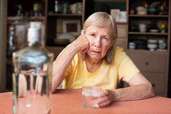 frau mit hand auf wange beim trinken schnaps