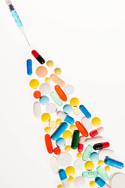 Close-up view of colorful pills and syringe on white, medicine and healthcare concept