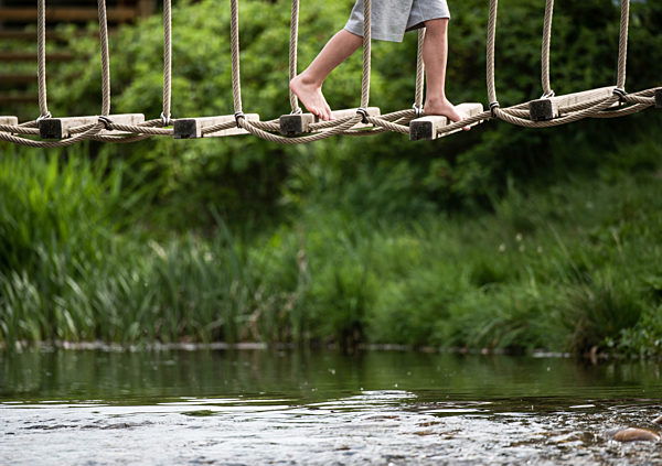 Kind geht über eine Hängebrücke