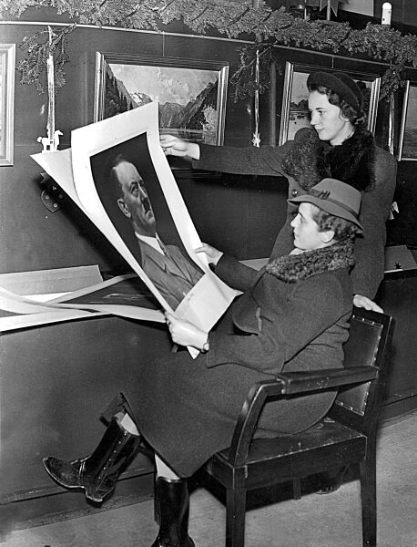Two women looking at illustrations, including a portrait of Hitler, 1937