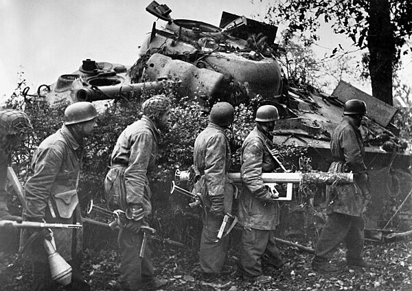German soldiers gathered behind the wreckage of an American M4 Sherman tank, carrying anti-tank weapons, Holland, 1944 (b/w photo)
