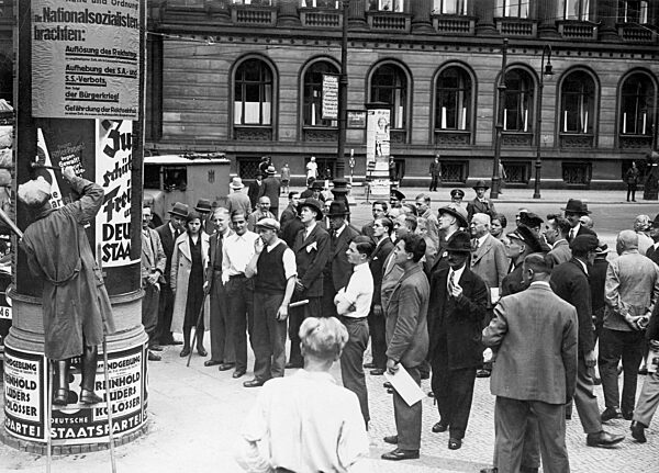 Pedestrians in front of advertising pillar with electoral advertisement, 1932
