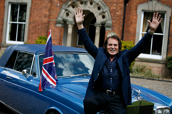 Engelbert Humperdinck poses for a photograph next to his car and a Union Jack flag