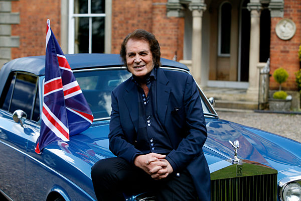 Engelbert Humperdinck poses for a photograph next to his car and a Union Jack flag