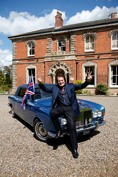 Engelbert Humperdinck poses for a photograph next to his car and a Union Jack flag