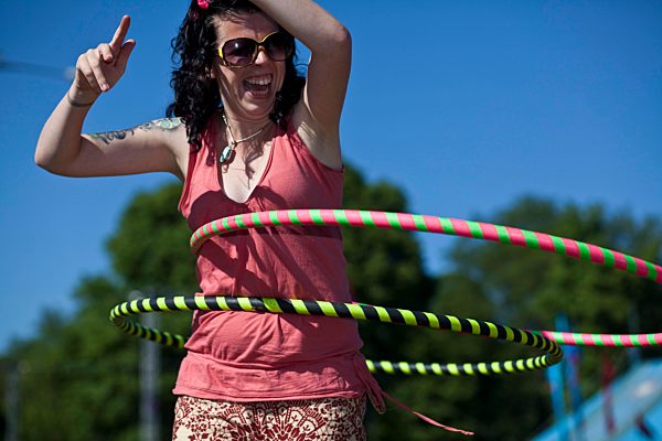 Woman laughs as she attempts to learn to hula hoop in a park in Brighton, 2010.