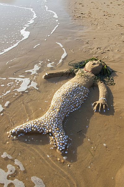 am Mittelmeerstrand aus Sand, Muschelschalen, Steinchen und Algen gestaltete Meerjungfrau, mermaid created of Sand, seashells, little stones and algae at the mediterrian beach