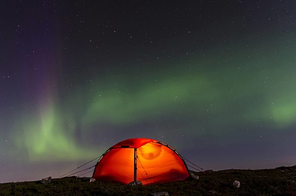 Nordlicht (Aurora borealis) ueber einem erleuchteten Zelt, Northern Lights (Aurora borealis) over an illuminated tent
