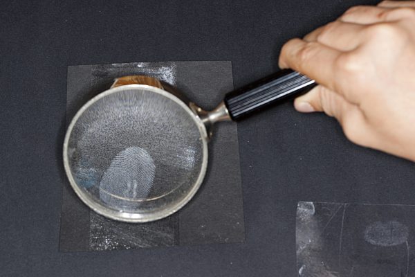 Fingerabdruecke nehmen, 5. Schritt: fixierter Fingerabdruck wird durch die Lupe betrachtet, taking fingerprints. Step 5: fixed fingerprint investigated with a lense