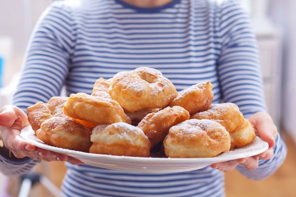 A woman holding a tray of Bulgarian doughnuts