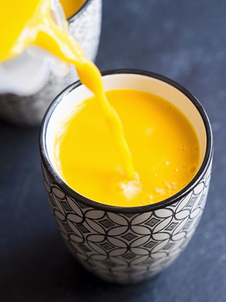 Selbstgemachte vegane Goldene Milch in Becher einschenken