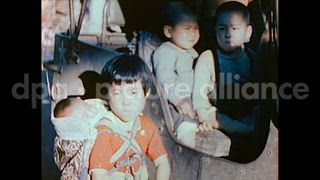 October 27, 1945 – Tokyo Japan: Woman and children stand on a street near a U.S. Army jeep in Tokyo, Japan.