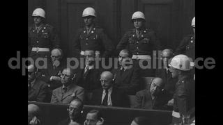 October 1946 – Nuremberg Germany: Justice Sir Geoffrey Lawrence reviewing events of World War 1 during Nuremberg trials; Nazi defendants look on.