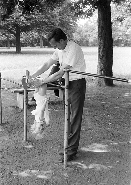 Vater mit Kind auf einem Spielplatz in Halle (Saale) im Bundesland Sachsen-Anhalt auf dem Gebiet der ehemaligen DDR, Deutsche Demokratische Republik