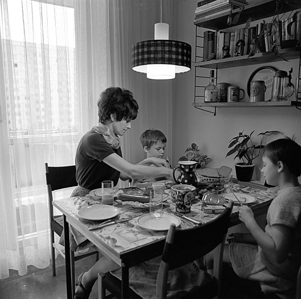 Zwei Mädchen sitzen mit ihrer Mutti am gedeckten Tisch beim Abendbrot in...