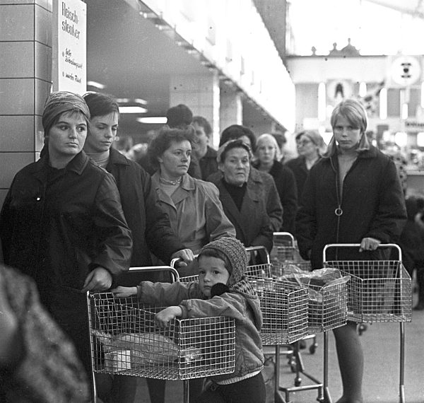 Kundinnen stehen mit ihren Einkaufswagen in der Schlange an der Wursttheke...