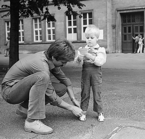 Ein Vater bindet seinem Kind die Schuhe zu, in Berlin, der ehemaligen Hauptstadt der DDR, Deutsche Demokratische Republik