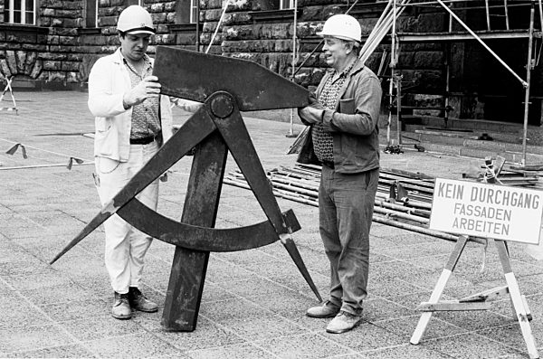 Arbeiter demontieren Mitte 1990 das DDR-Emblem am Hause des ehemaligen...