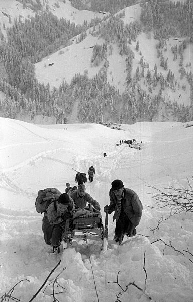 Rettungstrupp transportiert eine geborgene Person nach Lawinenabgängen bei Blons, 1954