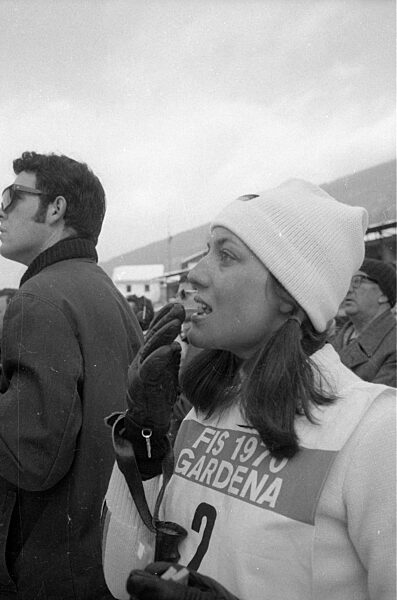 Skisportlerin schaut gebannt zu einer Piste hinauf, 1970