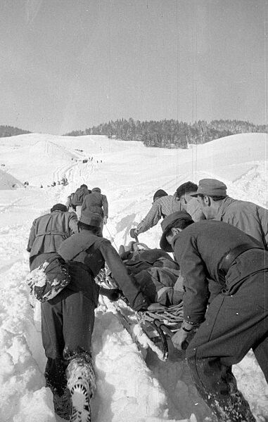 Rettungstrupp transportiert eine geborgene Person nach Lawinenabgängen bei Blons, 1954