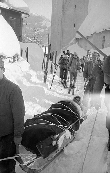Gerettetes Lawinenopfer auf einem Rettungsschlitten nach Lawinenabgang bei Blons, 1954
