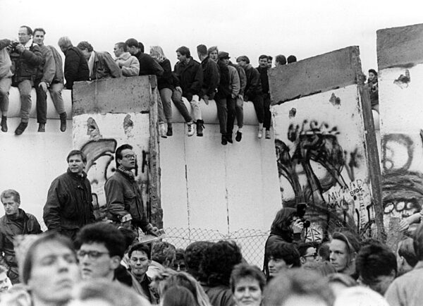 Menschen sitzen auf der Berliner Mauer,