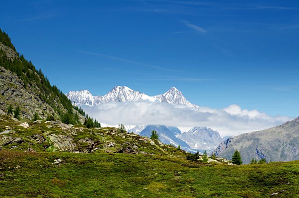 Snow-capped mountains and clouds and blue sky in Valais, Switzerland.