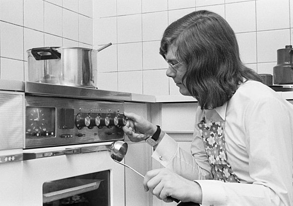 Siebziger Jahre, Menschen, junger Hobbykoch hockt vor dem Kochherd und reguliert die Kochtemperatur, Wilfried