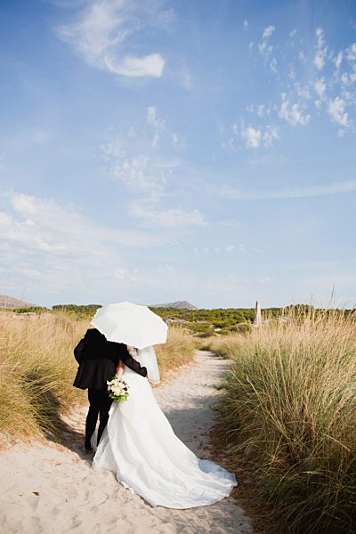 bride and groom walking under parasol