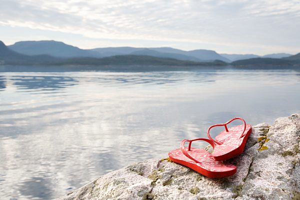 Flip flops on rock by sea and mountains