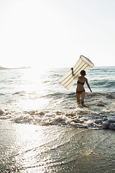 Woman with inflatable mattress on beach