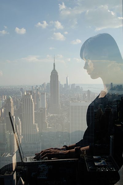 Woman using laptop against cityscape, New York, USA