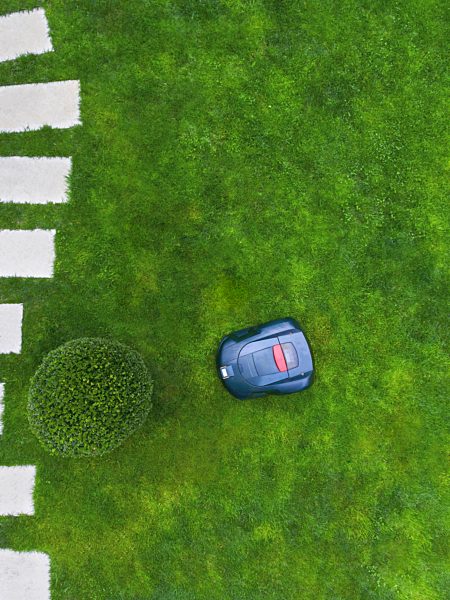 Germany, Bavaria, robotic lawn mower on meadow