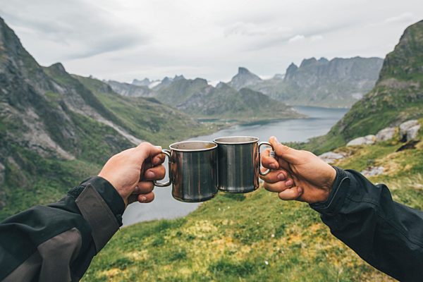 Norway, Lofoten, Moskenesoy, Two people toasting with tin cups