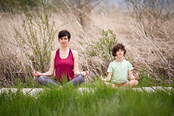 Mother and daughter doing yoga on boardwalk