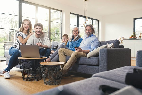 Extended family sitting on couch, using mobile devices