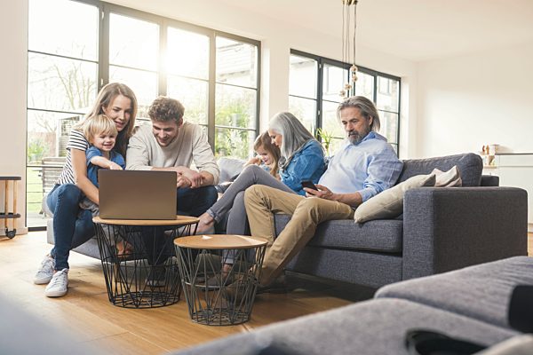 Extended family sitting on couch, using mobile devices