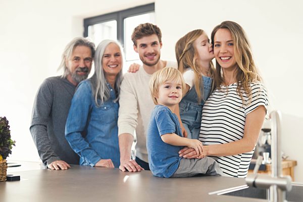 Happy family with grandparents and children standing in the kitchen