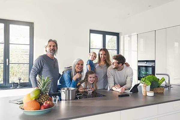 Happy family with grandparents and children standing in the kitchen