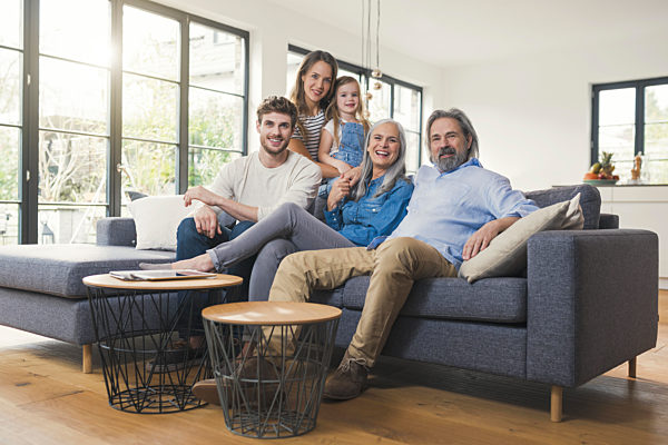 Extended family sitting on couch, smiling happily