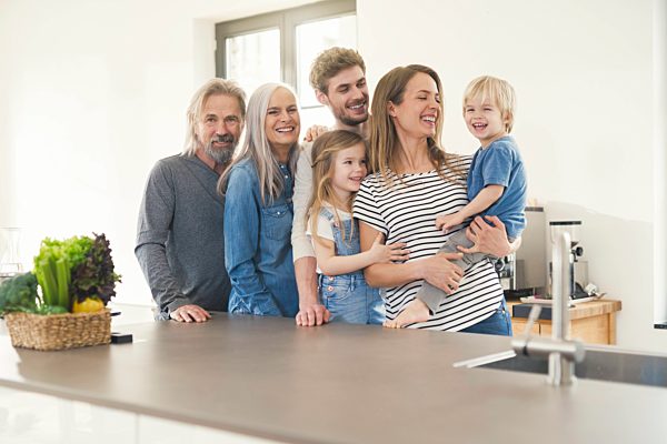 Happy family with grandparents and children standing in the kitchen