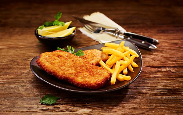 Pork escalope and French Fries on plate, lemon in bowl