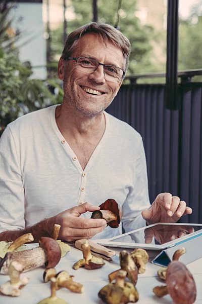Portrait of laughing man with tablet holding scarletina bolete