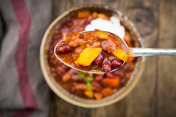 Chili con Carne with coriander and sour cream, spoon, close-up