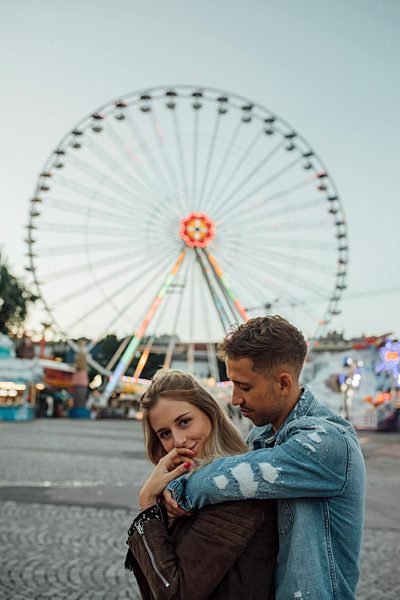 Young couple in love, embracing at a funfair