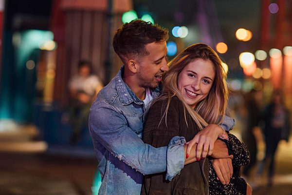 Young couple in love, embracing at a funfair