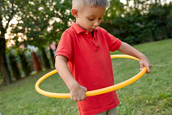 Boy playing with hula hoop in garden
