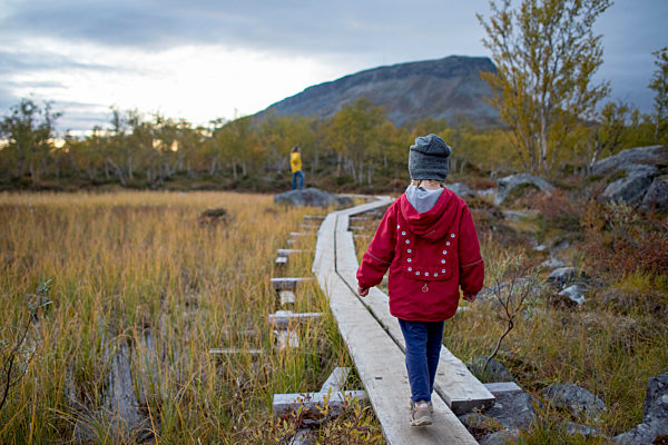 Finland, Lappland, Kilpisjaervi, girl on boardwalk, rear view