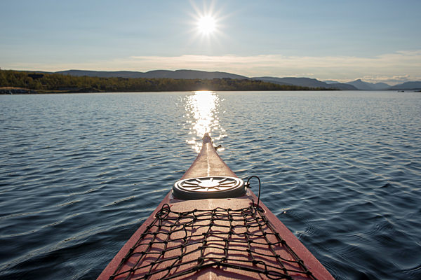 Finland, Lappland, Kilpisjaervi, canoe on lake against the sun